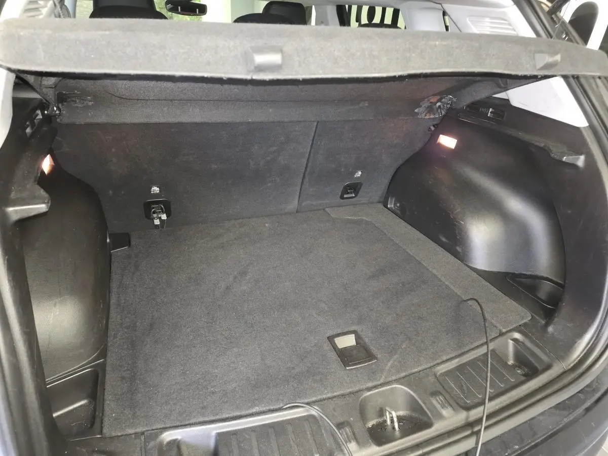 Coffre ouvert vu de l'arrière du Jeep Compass Trailhawk noir, montrant l'espace de chargement et l'éclairage intérieur.