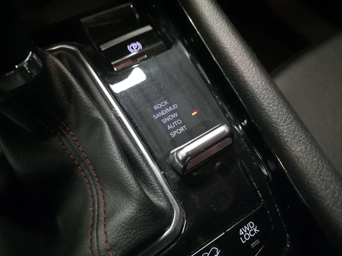 Gros plan sur la console centrale noire du Jeep Compass Trailhawk avec sélecteur modes tout-terrain et frein électrique.