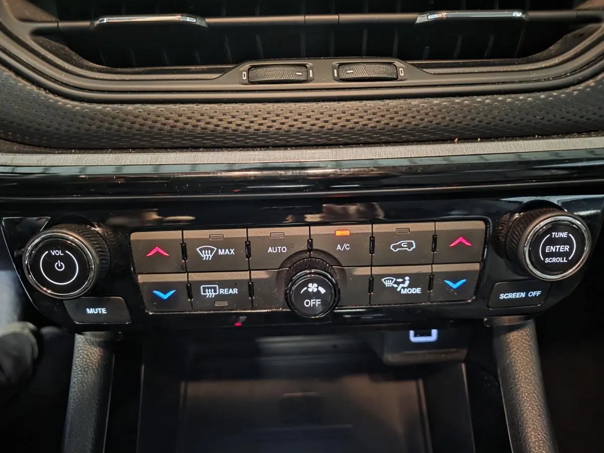 Vue rapprochée du panneau de commande de climatisation et audio noir du Jeep Compass Trailhawk 2022.