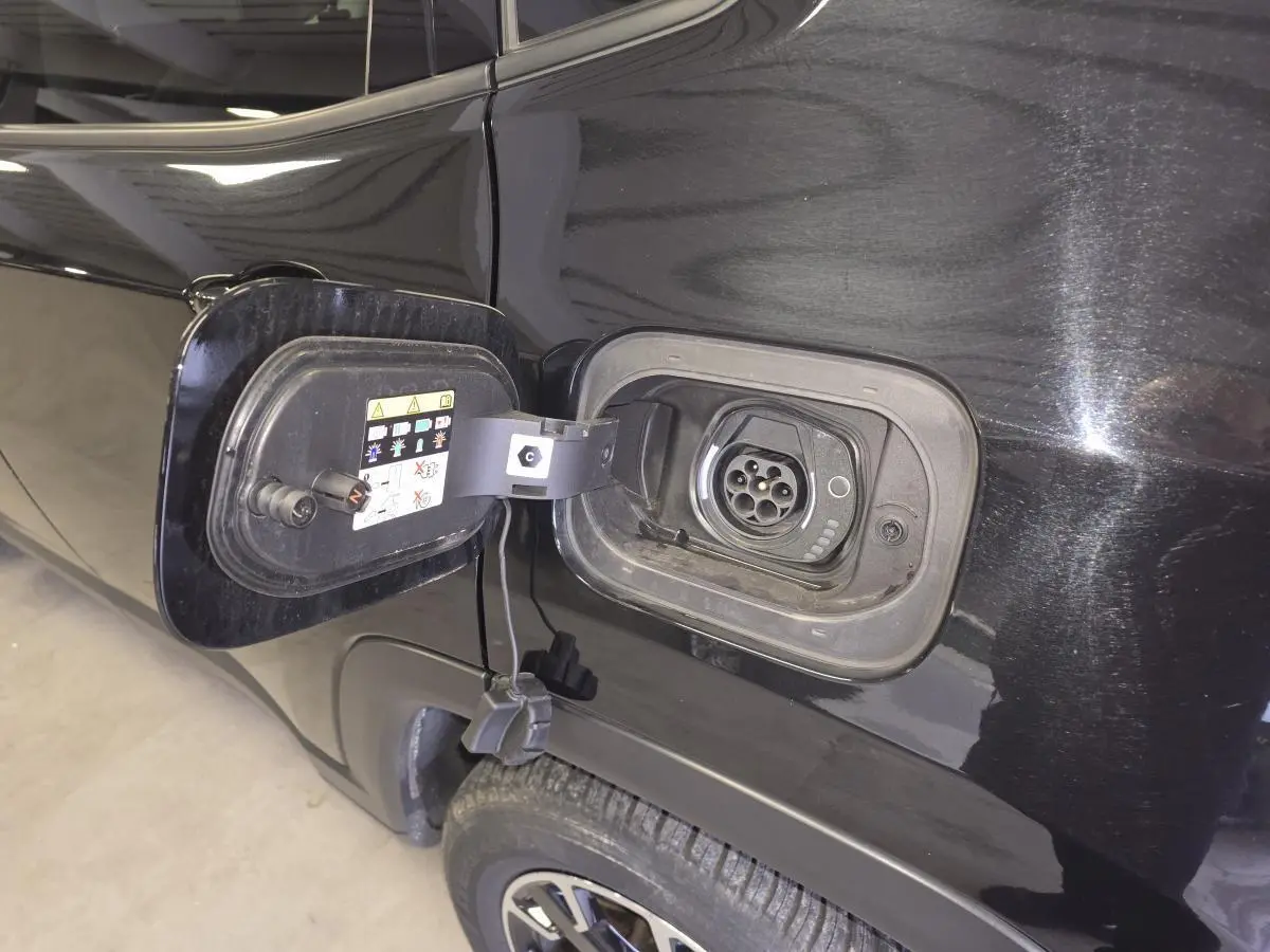 Gros plan sur la trappe de recharge côté gauche d’un Jeep Compass Trailhawk noir avec prise Type 2 visible.
