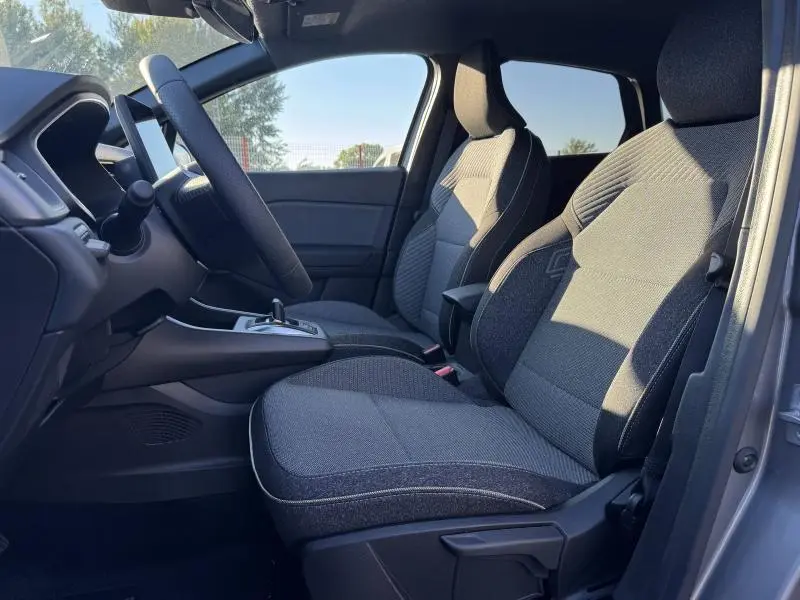 Vue intérieure côté conducteur du Renault Captur 2025 montrant les sièges tissu gris et la console centrale.