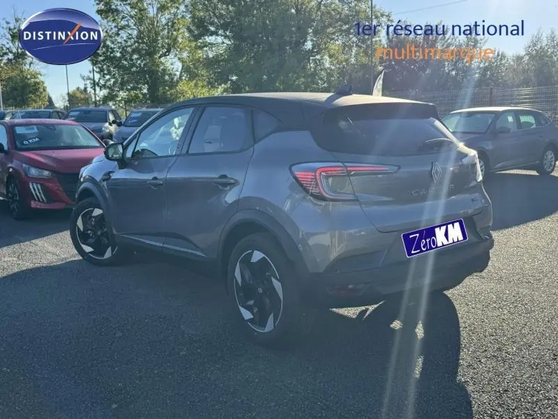 Vue 3/4 arrière droite d'un Renault Captur gris métallisé avec jantes noires et blanches, stationné en extérieur.
