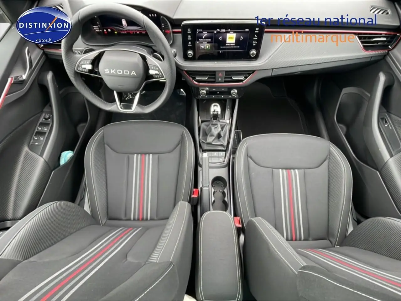 Vue intérieure frontale du Skoda Kamiq noir, mettant en valeur les sièges sport avec bandes rouges et grises et le tableau de bord moderne.