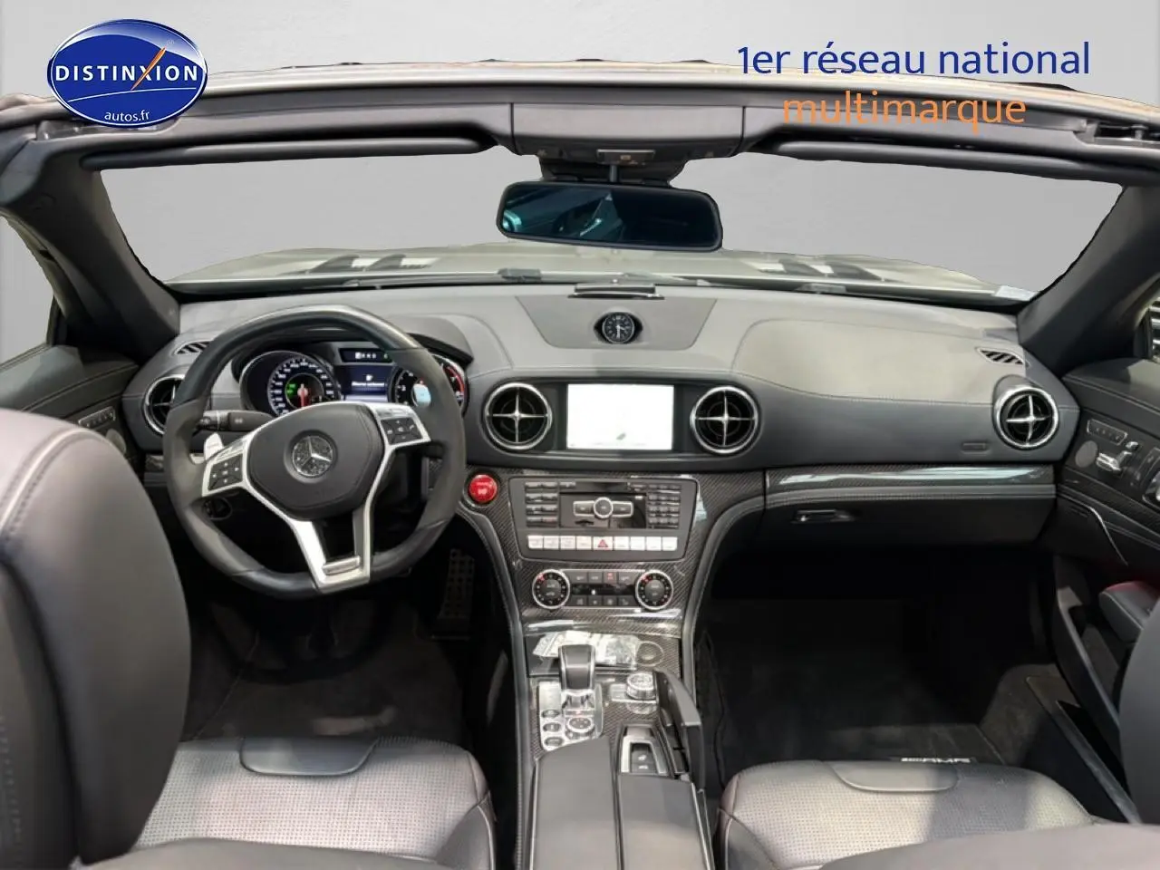Vue intérieure avant d'une Mercedes Classe SL 63 AMG Speedshift MCT 2013 avec tableau de bord noir et inserts carbone.