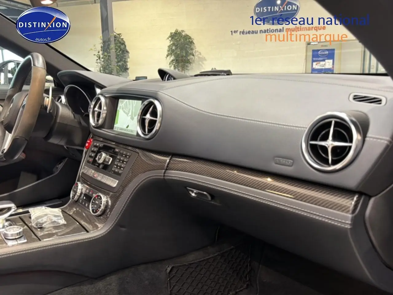 Vue intérieure côté passager du tableau de bord en cuir noir avec inserts carbone et écran GPS de la Mercedes Classe SL 63 AMG.