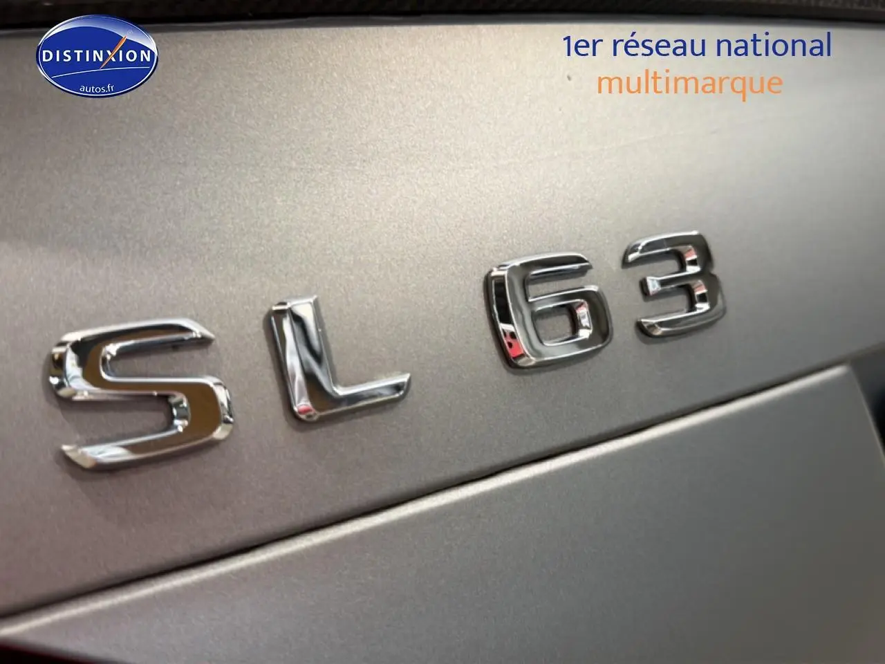 Gros plan sur l’inscription chromée SL 63 sur la carrosserie grise métallisée d’une Mercedes Classe SL.