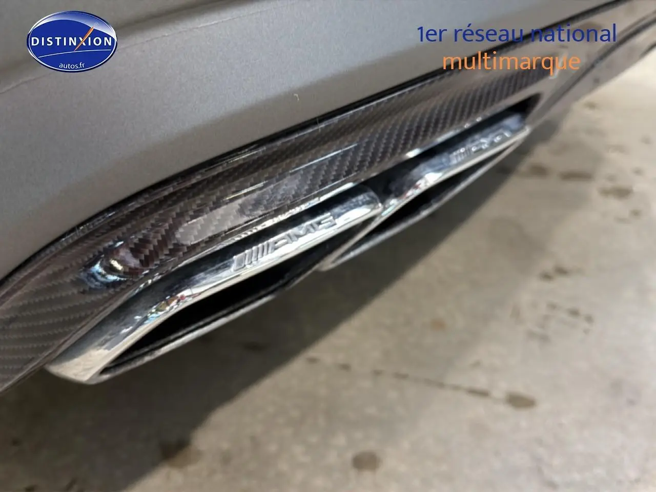 Gros plan sur la sortie d’échappement chromée AMG intégrée dans le diffuseur arrière gris de la Mercedes Classe SL 63 AMG.