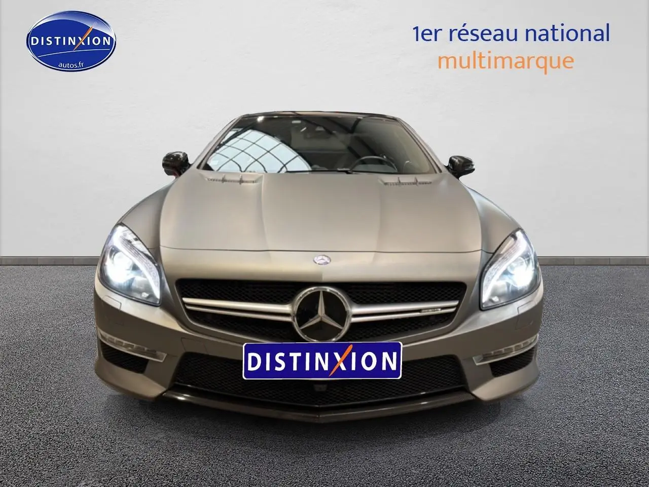 Vue frontale d'une Mercedes Classe SL 63 AMG gris métallisé avec phares allumés et calandre chromée.