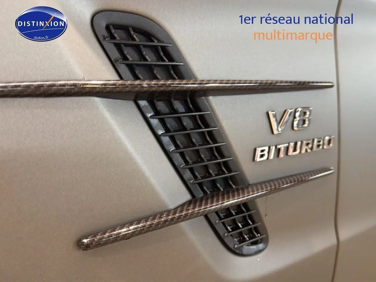 Détail de l'aération latérale droite en carbone et logo V8 BITURBO sur carrosserie grise d'une Mercedes Classe SL 63 AMG.