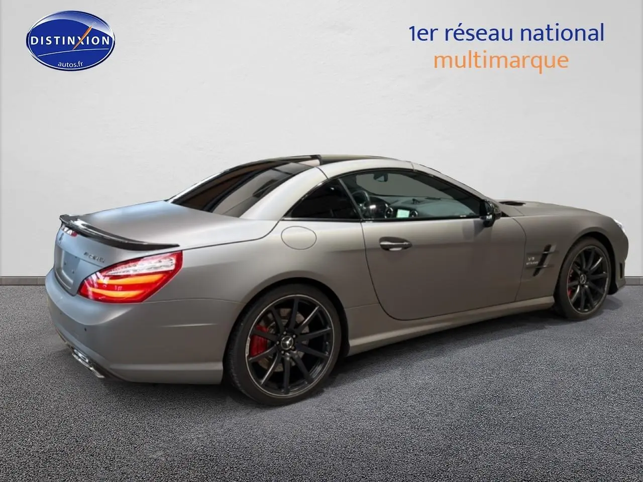 Mercedes Classe SL 63 AMG gris vue 3/4 arrière droit, avec jantes noires et becquet arrière distinctif.