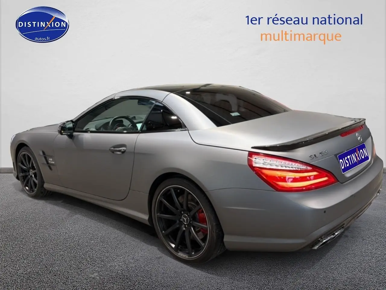 Vue 3/4 arrière droite d'une Mercedes Classe SL 63 AMG gris mat avec jantes noires et becquet arrière.