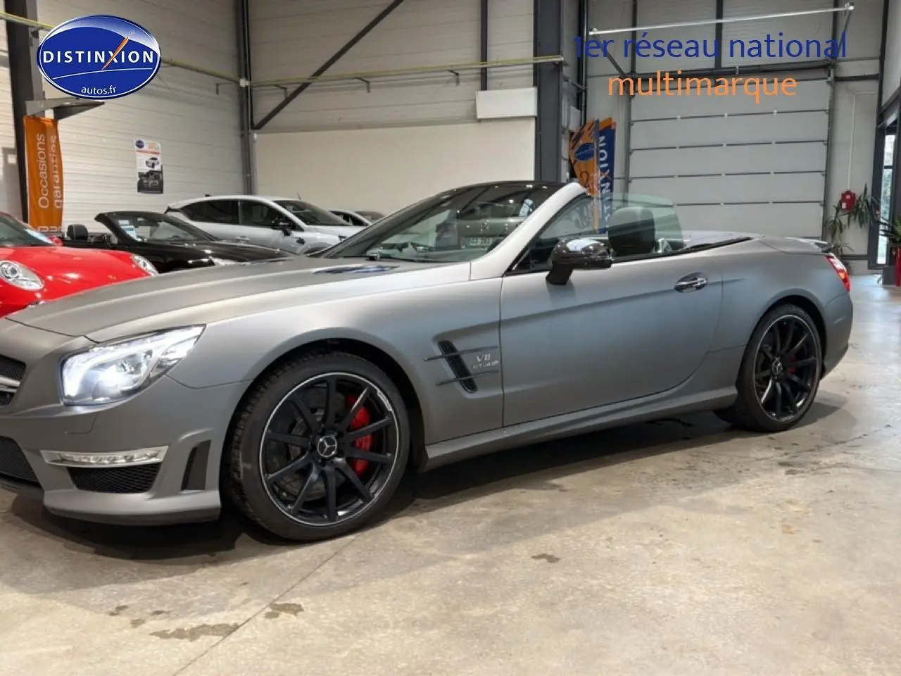 Mercedes Classe SL 63 AMG gris mat vue de profil droit, capote ouverte et jantes noires avec étriers rouges.