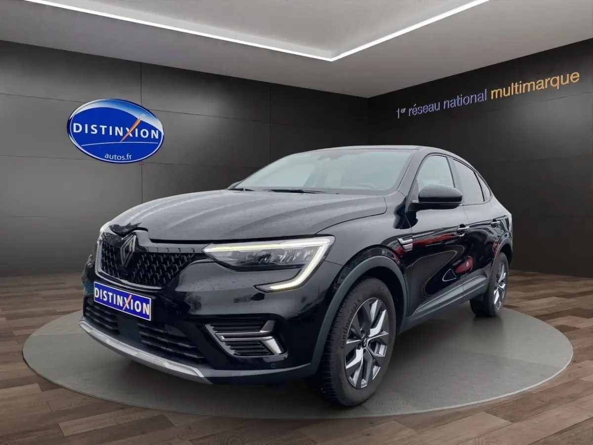 Renault Arkana noir en 3/4 avant droit, avec phares LED allumés et jantes alliage visibles en showroom.
