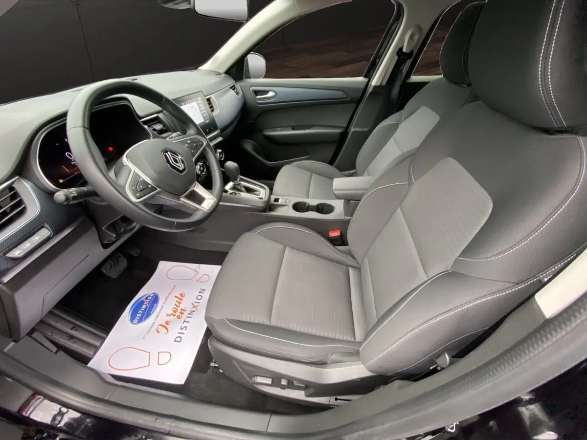Vue intérieure côté conducteur de la Renault Arkana noire 2024, montrant sièges en tissu et volant multifonctions.