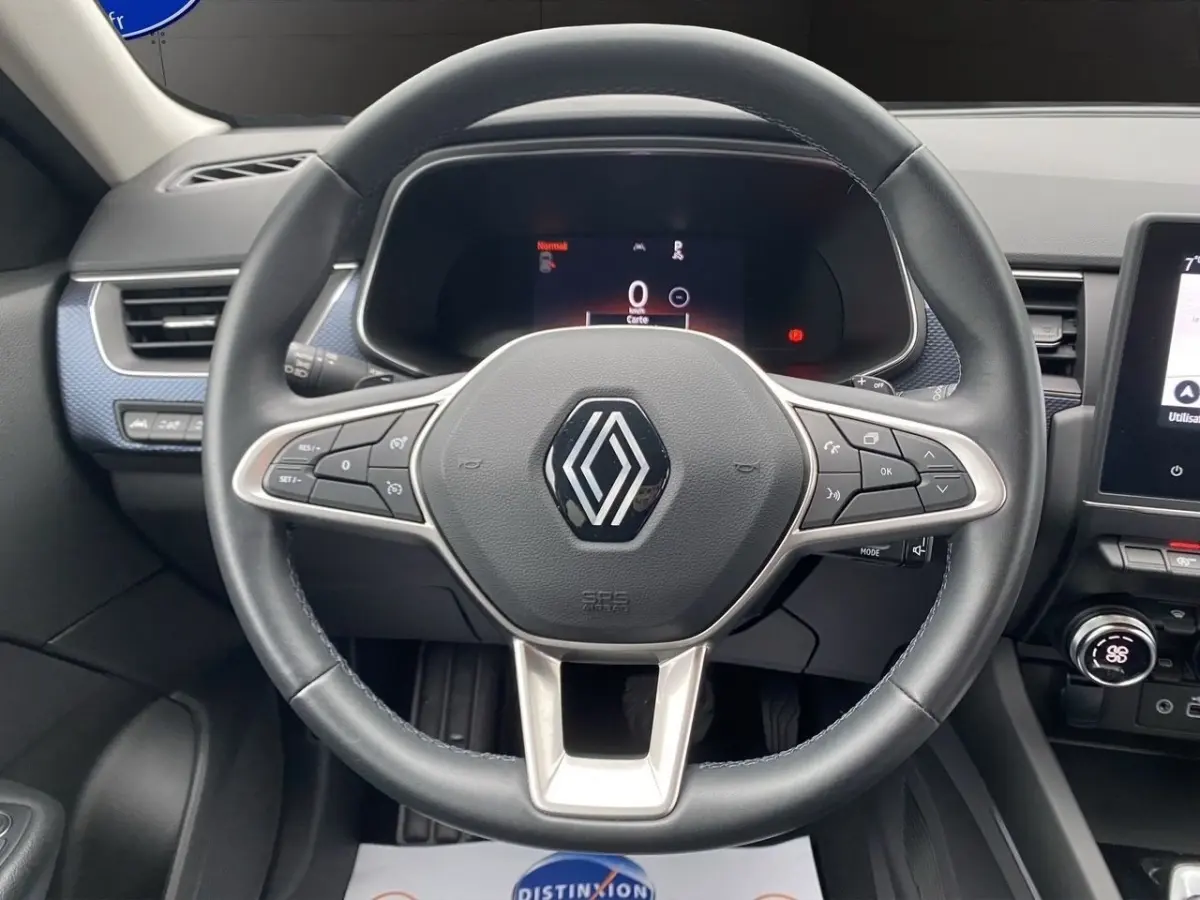 Vue centrée sur le volant cuir noir de la Renault Arkana 2024 avec tableau de bord numérique et écran tactile latéral.