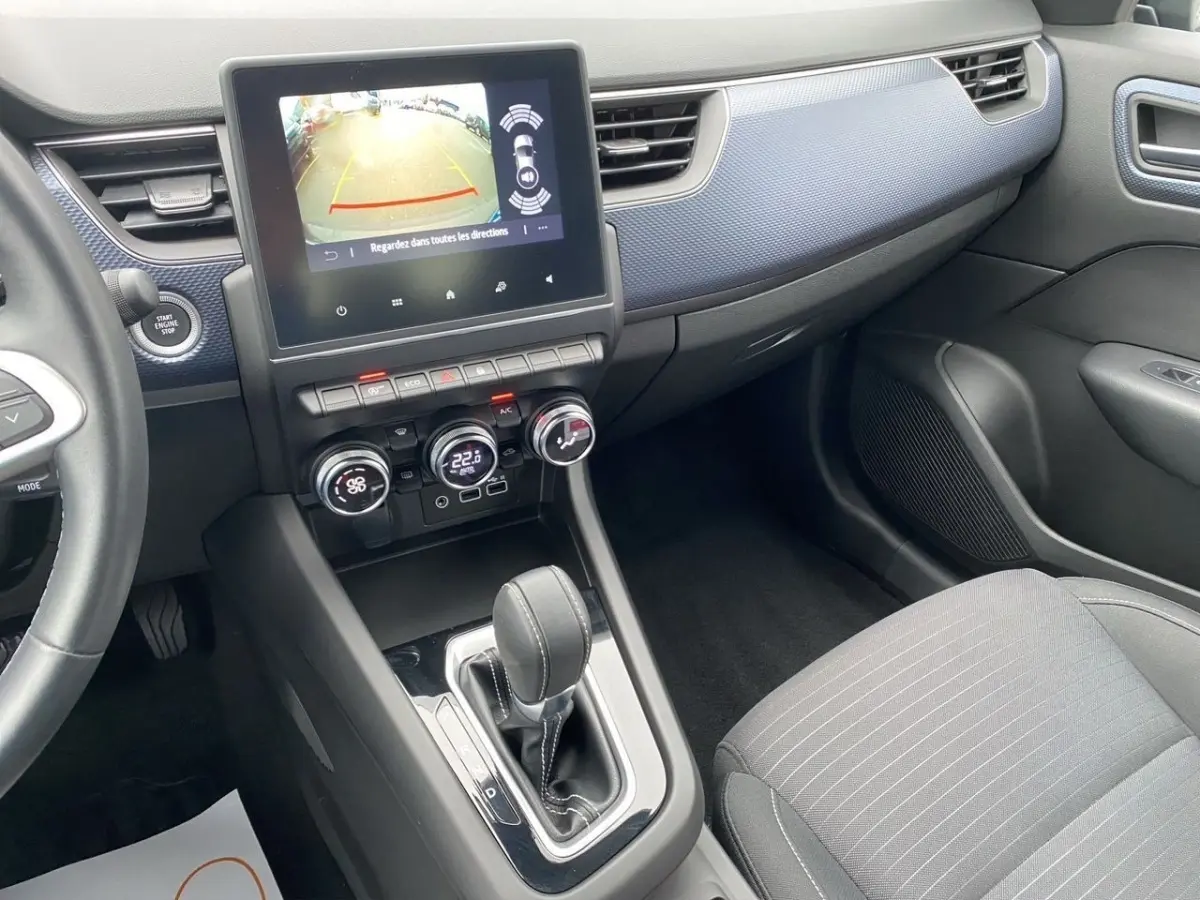 Vue intérieure côté passager du tableau de bord et console centrale de la Renault Arkana noire avec écran tactile et levier de boîte auto.