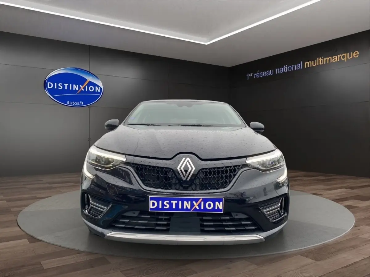 Vue avant d’une Renault Arkana noire 2024 avec calandre noire et phares LED allumés en showroom.
