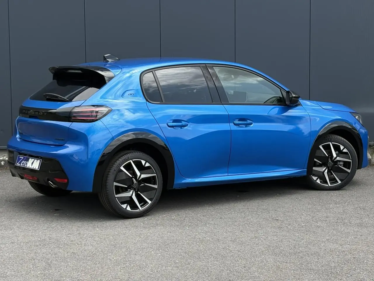 Peugeot 208 Hybrid 110 GT bleu Vertigo vue de profil côté droit avec jantes alliage bi-tons et toit noir.