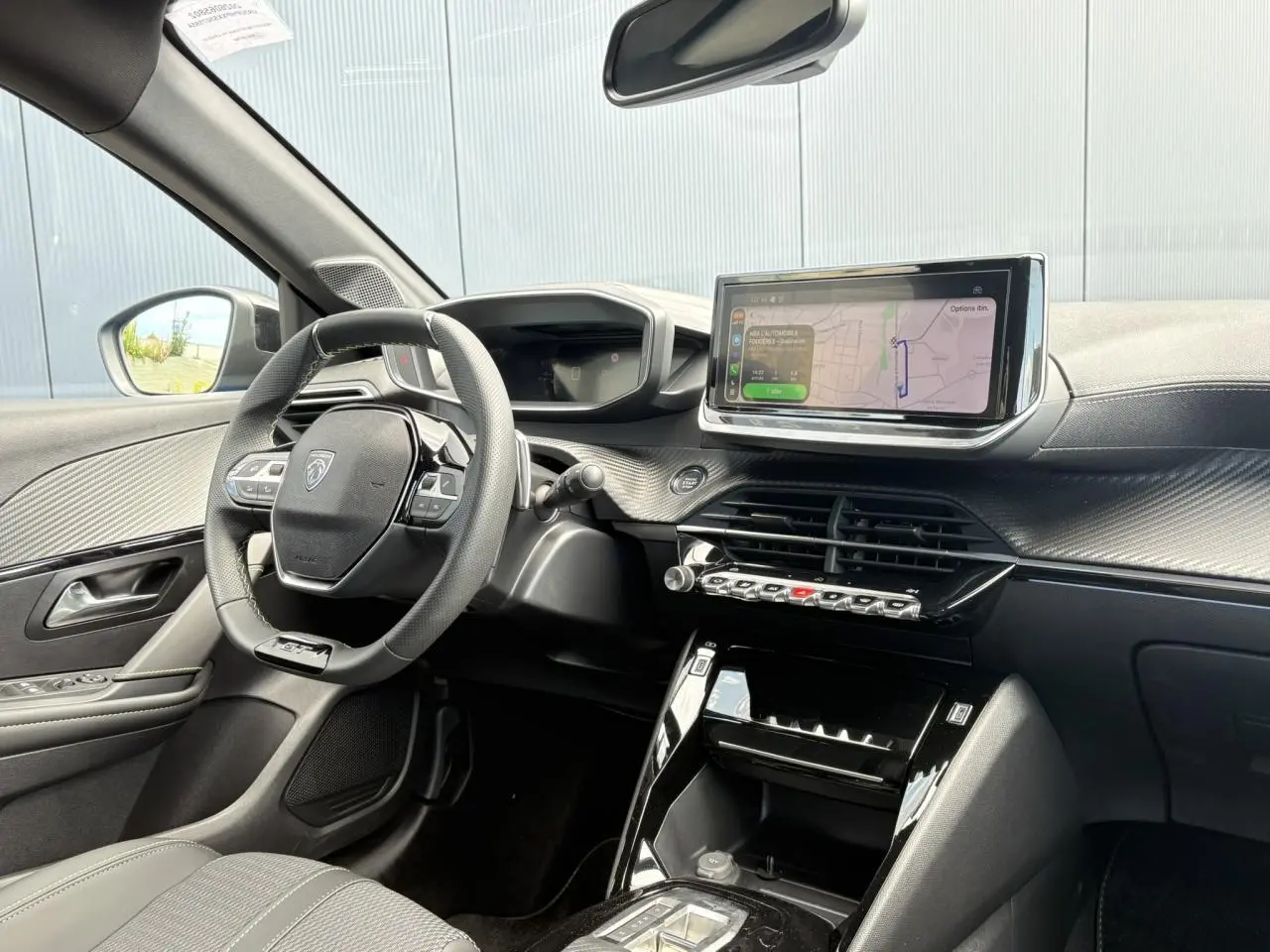 Vue intérieure côté conducteur du Peugeot 208 Hybrid 110 GT avec tableau de bord numérique et écran tactile central.