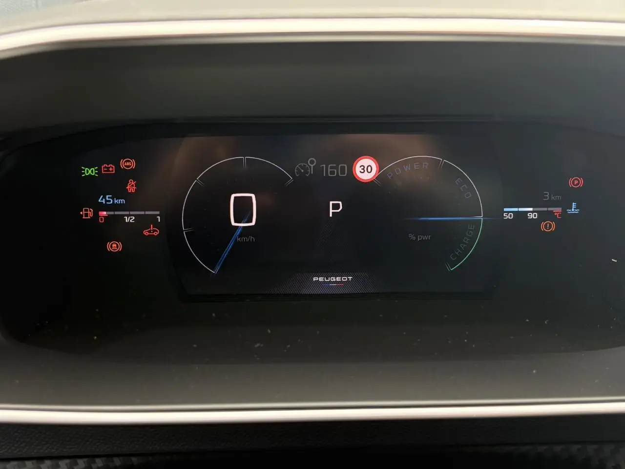 Tableau de bord numérique de Peugeot 208 Hybrid 110 GT affichant vitesse, mode parking et alertes, vue de face.