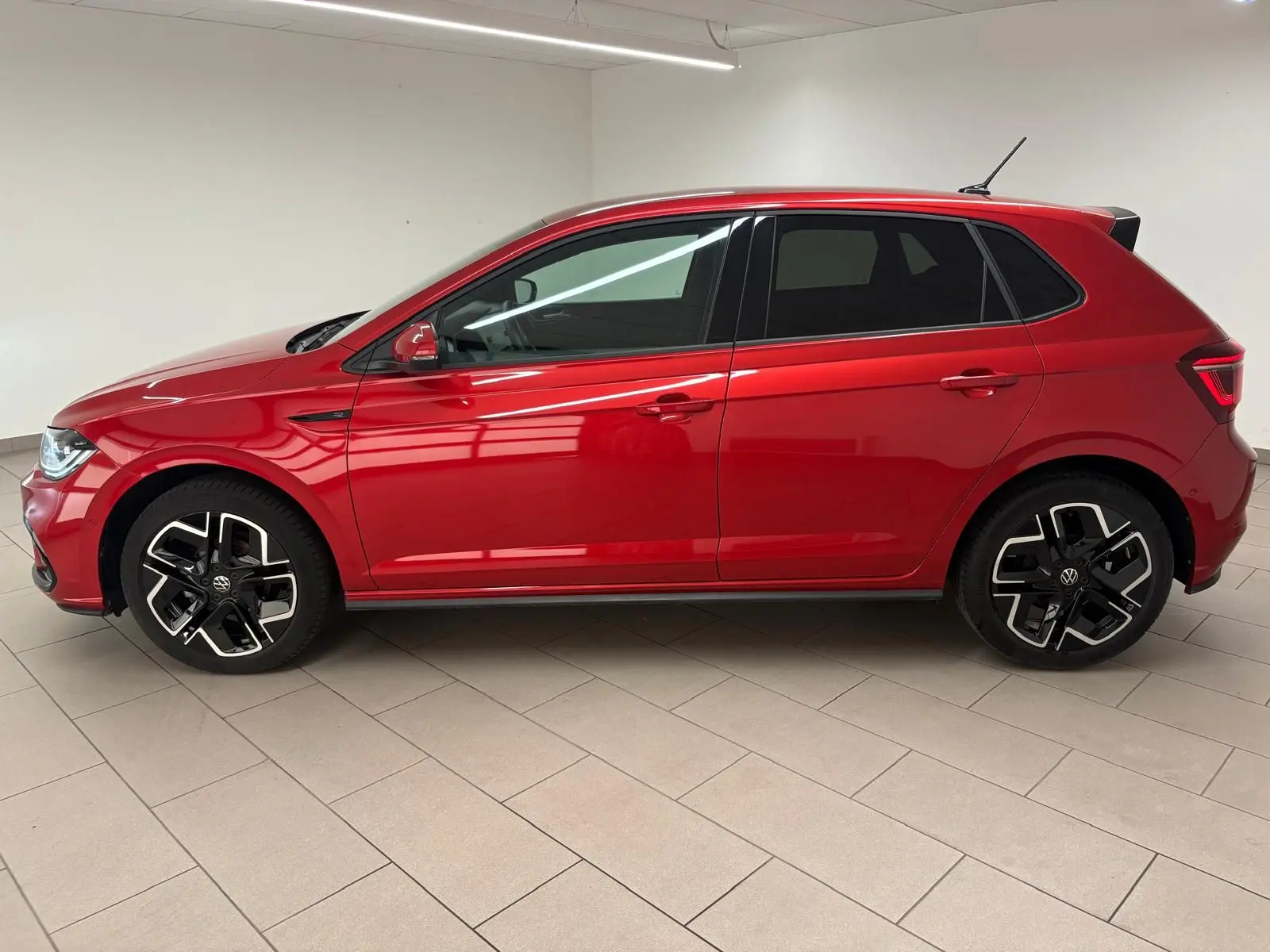 Vue de profil côté gauche d'une Volkswagen Polo 2025 Rouge Roi métallisée avec jantes R-Line distinctives.