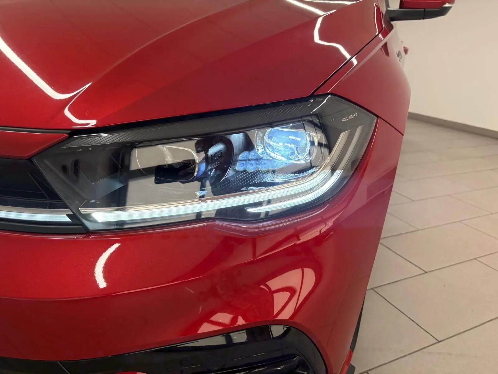 Gros plan sur le phare avant droit d'une Volkswagen Polo Rouge Roi 2025 avec peinture métallisée et signature lumineuse LED.