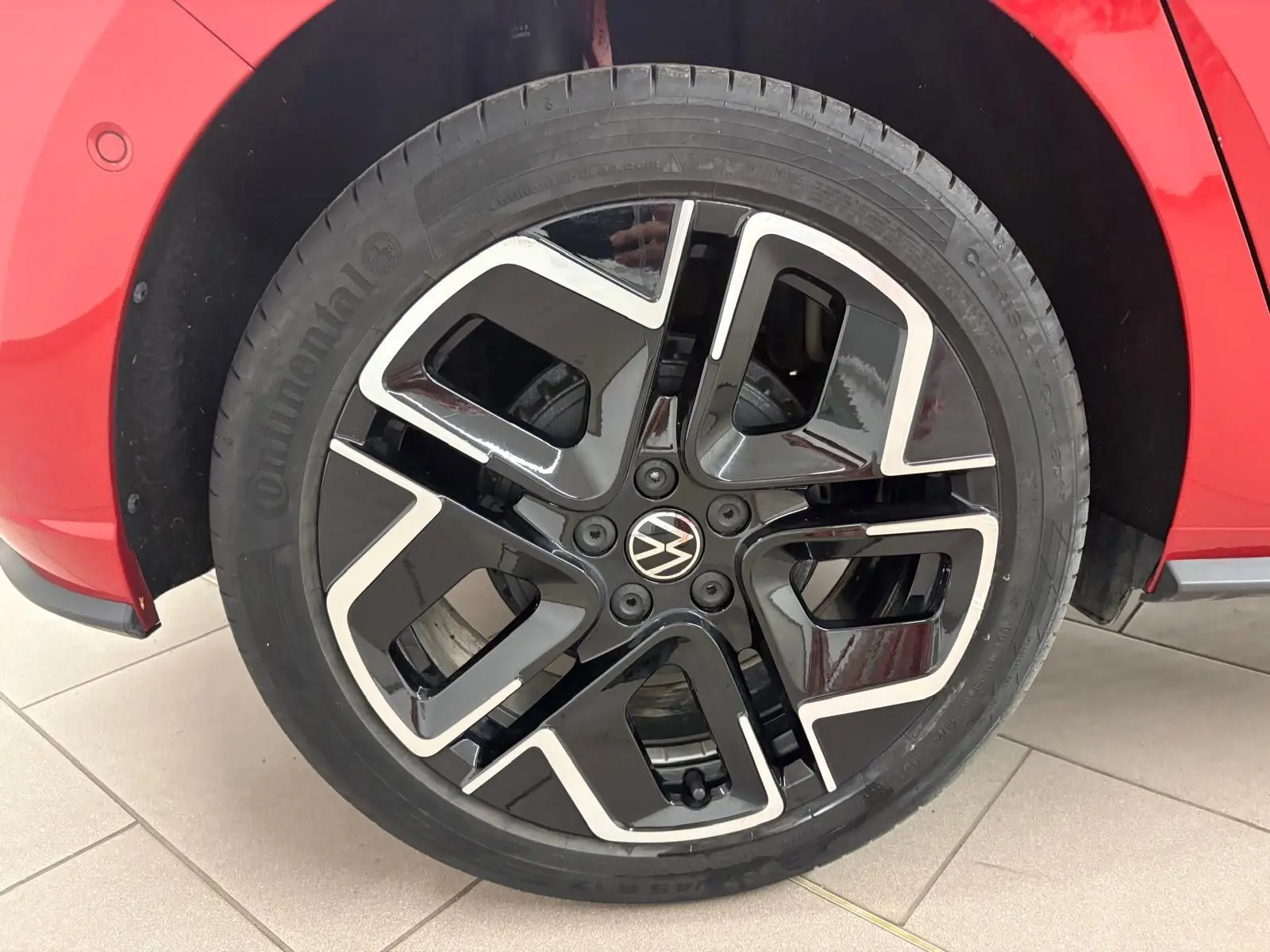 Gros plan sur la roue avant droite d’une Volkswagen Polo Rouge Roi, jante alliage noir et argent au design moderne.