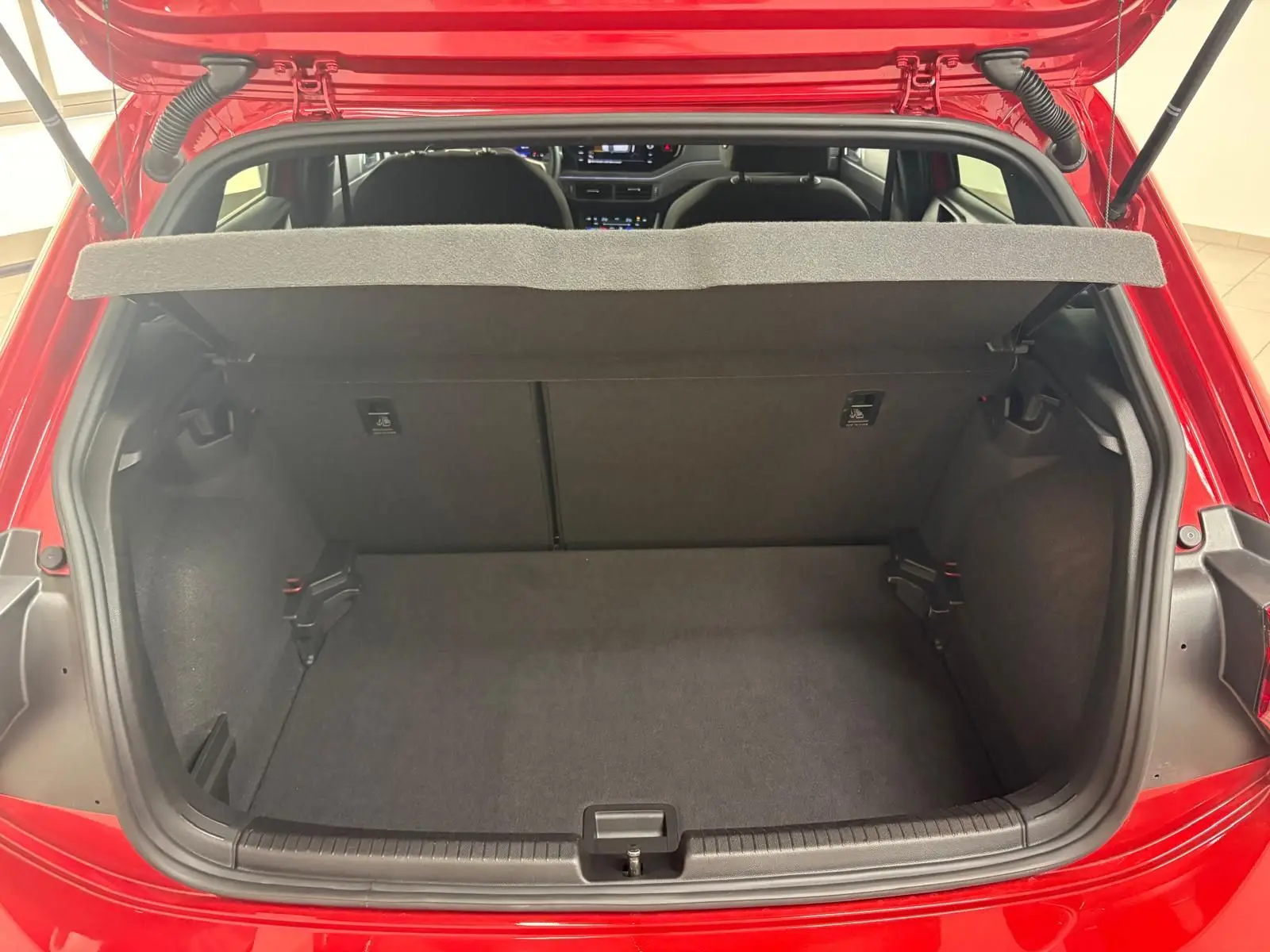 Vue arrière du coffre ouvert d'une Volkswagen Polo Rouge Roi 2025, montrant l'espace de rangement vide et la tablette cache-bagages.