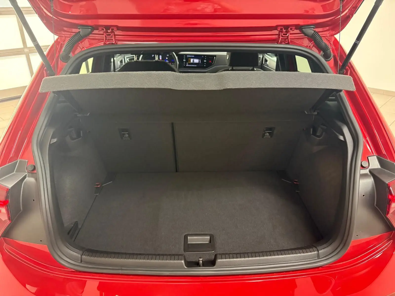 Coffre ouvert d'une Volkswagen Polo Rouge Roi 2025, vue arrière montrant l'espace de chargement et l'intérieur du véhicule.