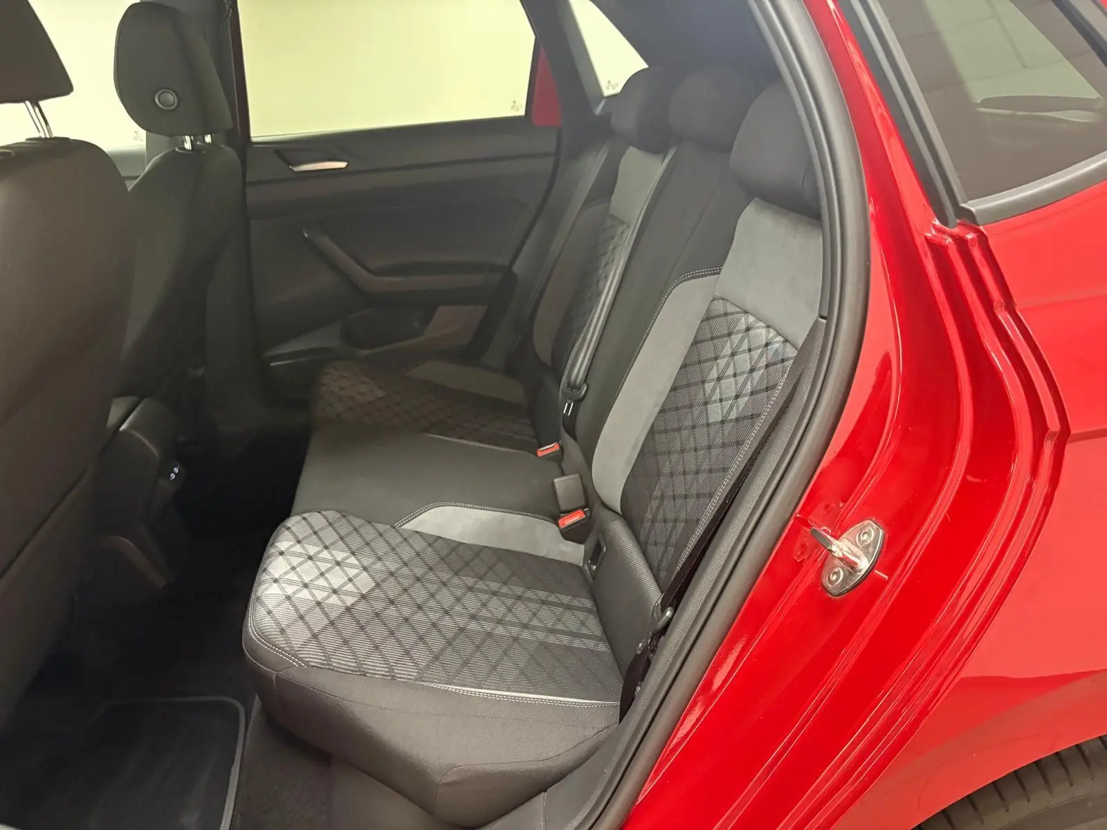 Vue intérieure côté arrière droit de la Volkswagen Polo Rouge Roi, montrant les sièges arrière en tissu à motifs géométriques.