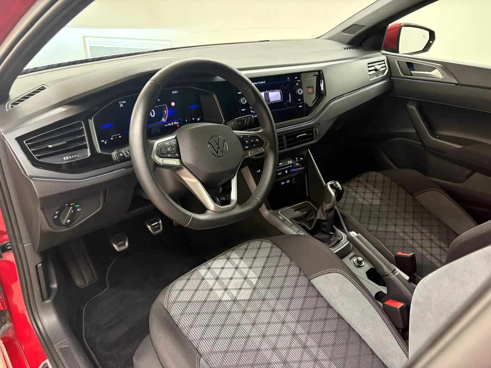 Vue intérieure côté conducteur de la Volkswagen Polo Rouge Roi 2025, volant multifonction et sièges tissu à motifs.