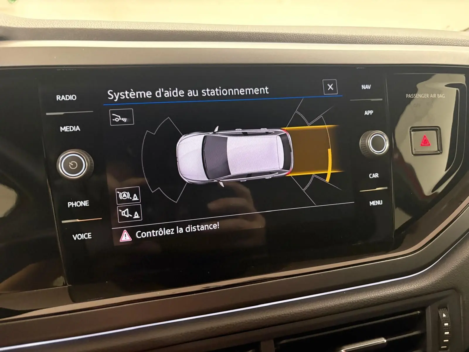 Écran central du système d'aide au stationnement de la Volkswagen Polo 2025 affichant une vue aérienne du véhicule en gris.