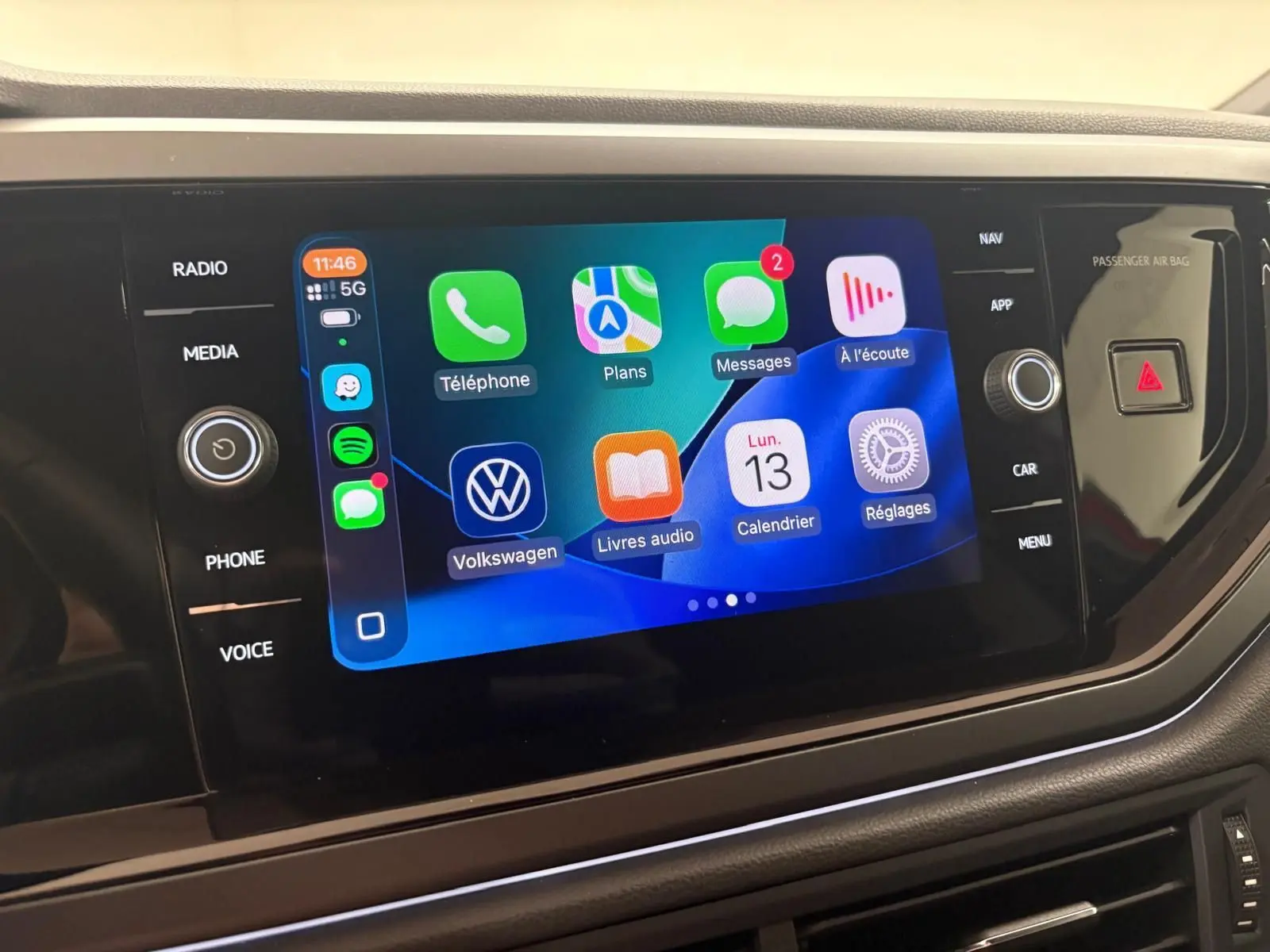 Écran tactile central de la Volkswagen Polo 2025 affichant les applications connectées, entouré de commandes noires brillantes.