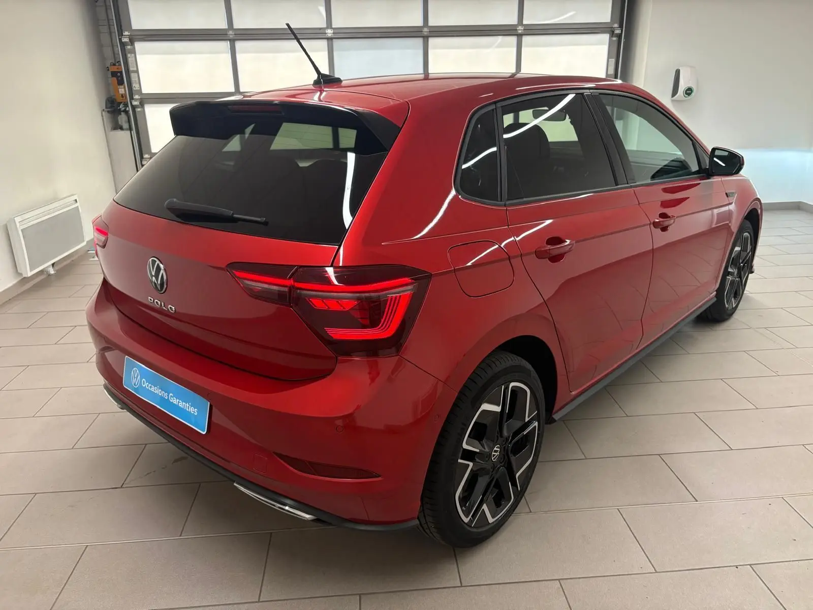 Vue 3/4 arrière droite d'une Volkswagen Polo 2025 Rouge Roi métallisée avec finition R-Line et jantes alliage distinctives.