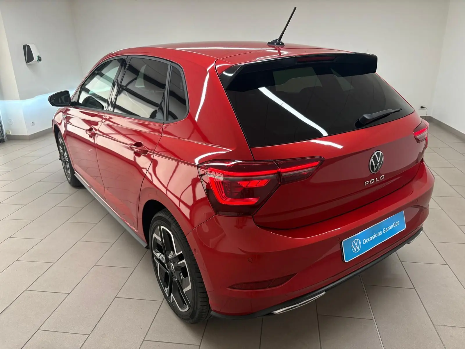 Vue 3/4 arrière droite d'une Volkswagen Polo 2025 Rouge Roi métallisée avec jantes R-Line et vitres teintées.