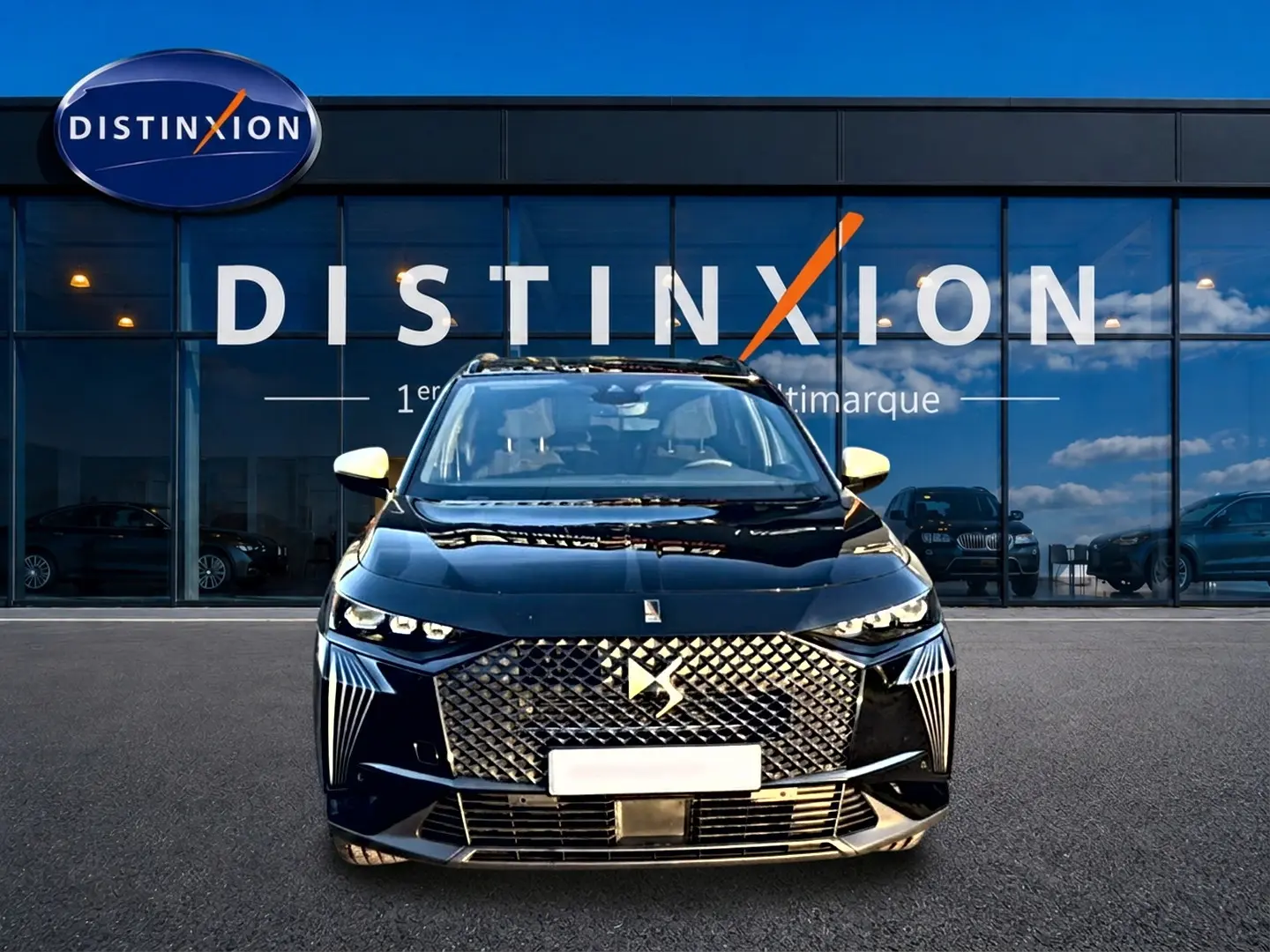 Vue avant d'un DS7 noir 2026 avec calandre diamantée et phares LED distinctifs, devant une vitrine Distinxion.