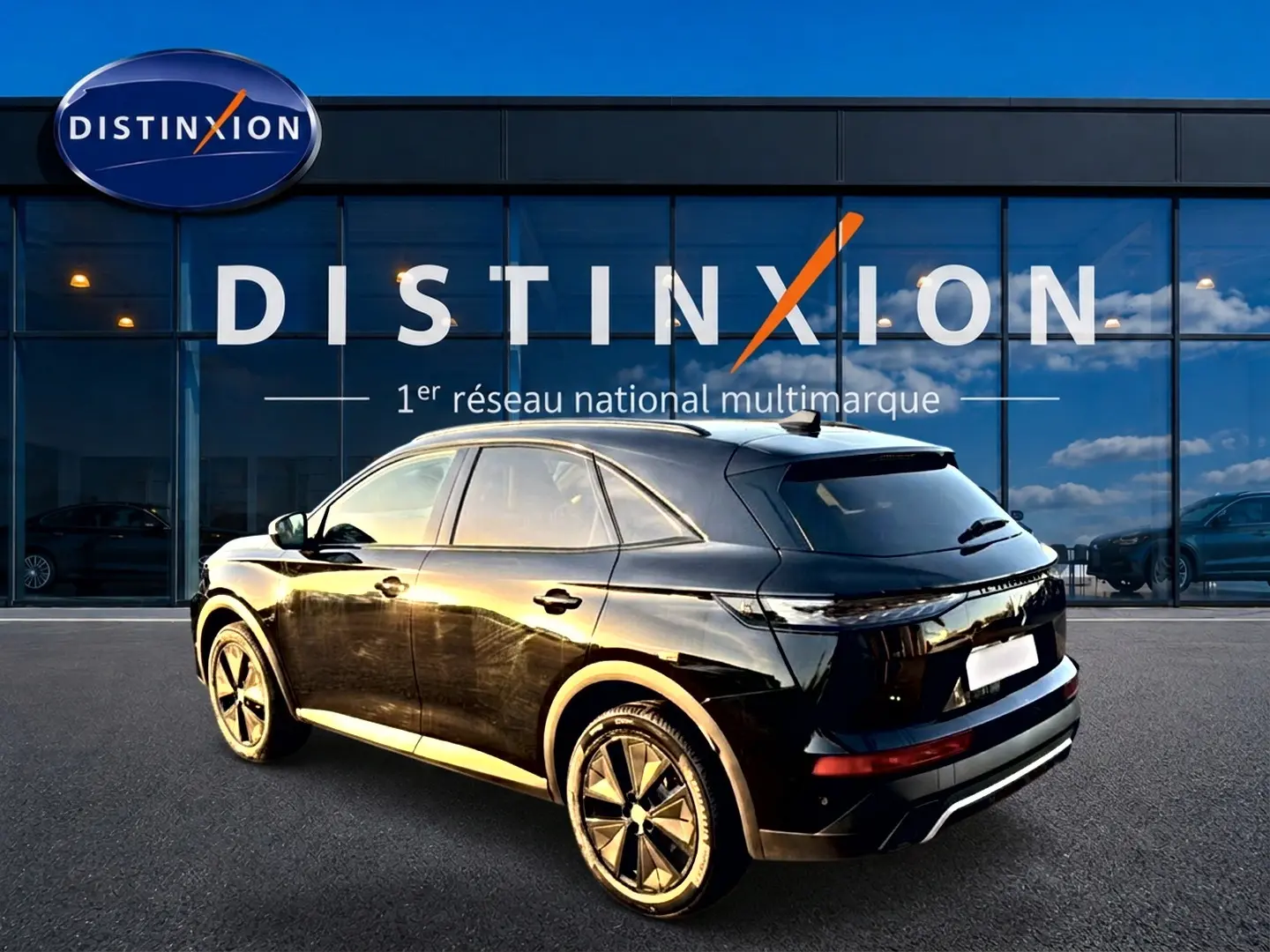 DS7 noir vue 3/4 arrière droit, avec jantes alu et vitres arrière surteintées devant un bâtiment Distinxion.