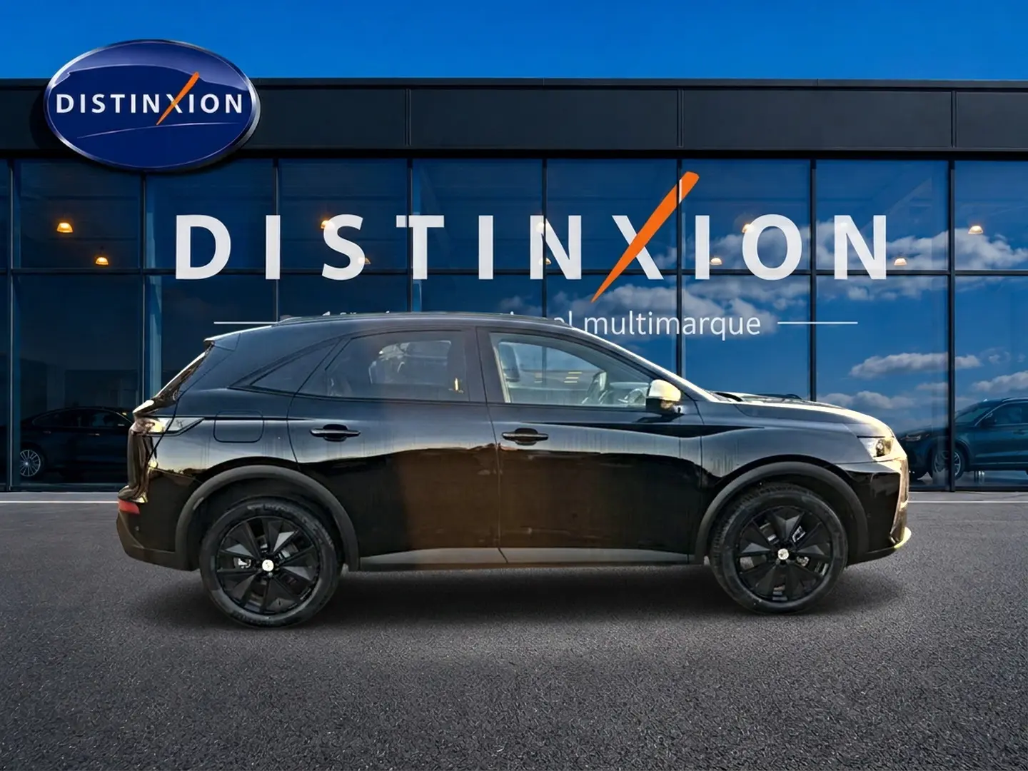 Vue latérale gauche d'un DS7 noir 2026 garé devant une vitrine avec logo Distinxion, jantes noires visibles.