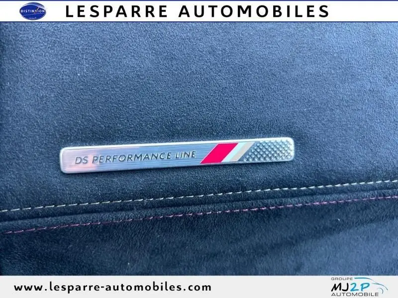 Gros plan sur l'écusson DS Performance Line sur un revêtement intérieur gris foncé avec surpiqûres rouges du DS7 Crossback E-TENSE.