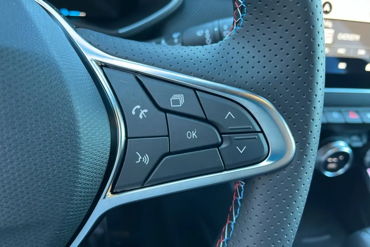 Gros plan sur les commandes multifonctions à droite du volant cuir perforé de la Renault Clio V E-Tech 145 Esprit Alpine Bose noire.