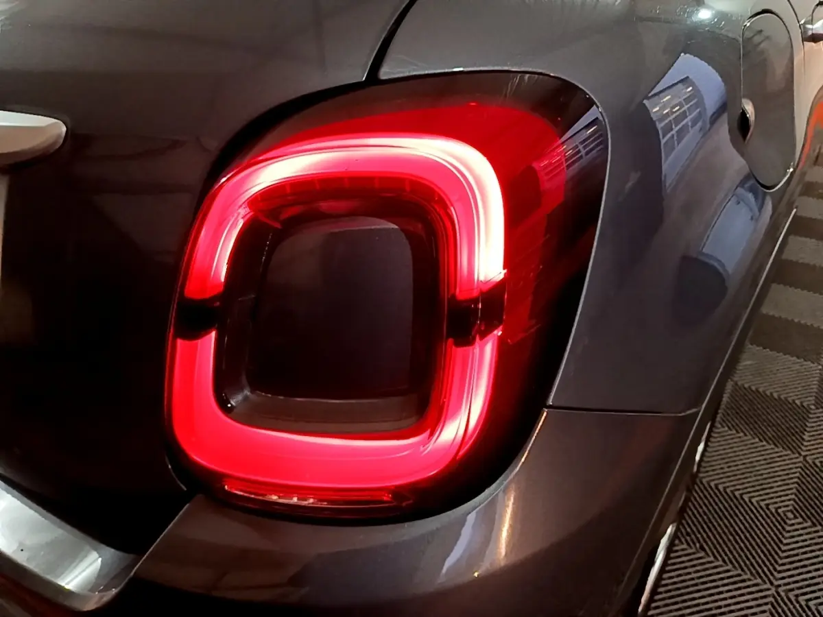 Gros plan sur le feu arrière droit rouge d’un FIAT 500X gris foncé, avec la trappe à carburant visible à côté.
