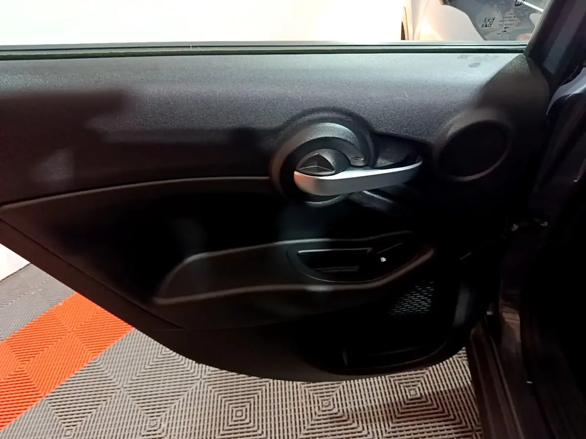 Vue intérieure du panneau de porte côté droit de la FIAT 500X gris foncé, mettant en valeur la poignée argentée et la commande de vitre.