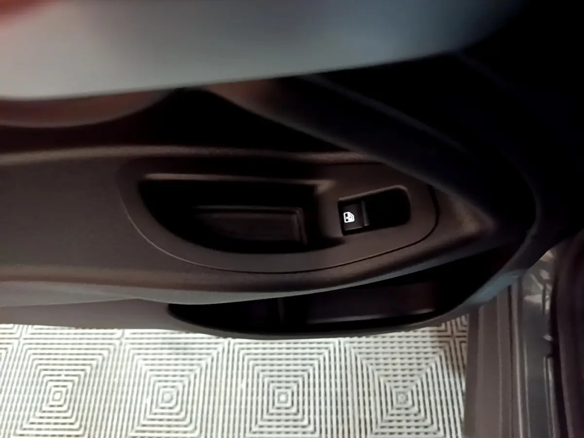 Gros plan sur la commande de verrouillage des portes côté conducteur du FIAT 500X gris foncé, intérieur sombre.