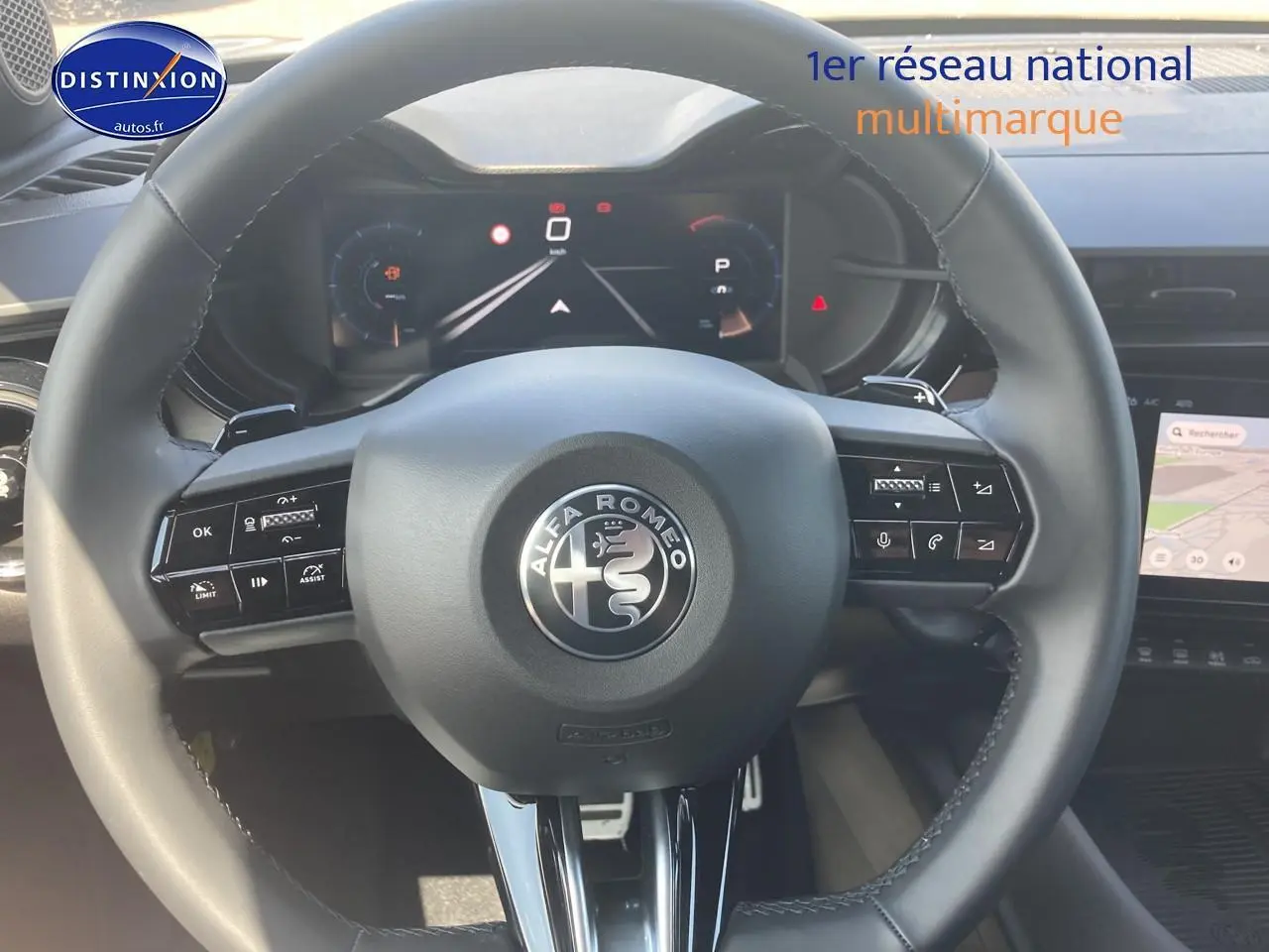 Vue centrée sur le volant cuir de l'Alfa Romeo Junior 1.2 hybride 2026 avec tableau de bord numérique et écran tactile.