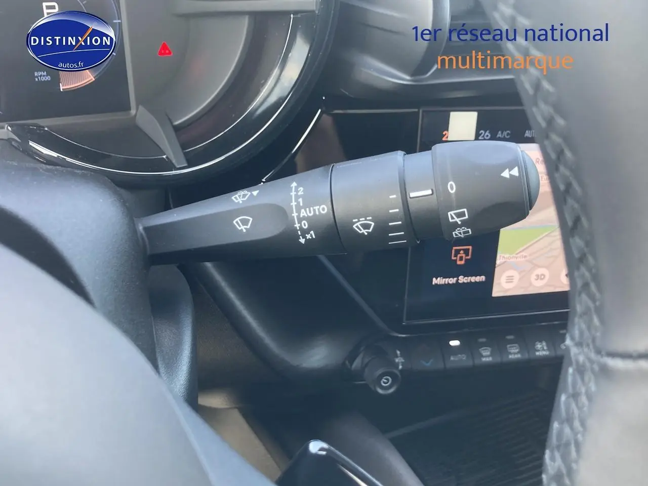 Gros plan sur le commodo d’essuie-glace côté gauche de l’intérieur d’une Alfa Romeo Junior gris/noir avec écran tactile visible.