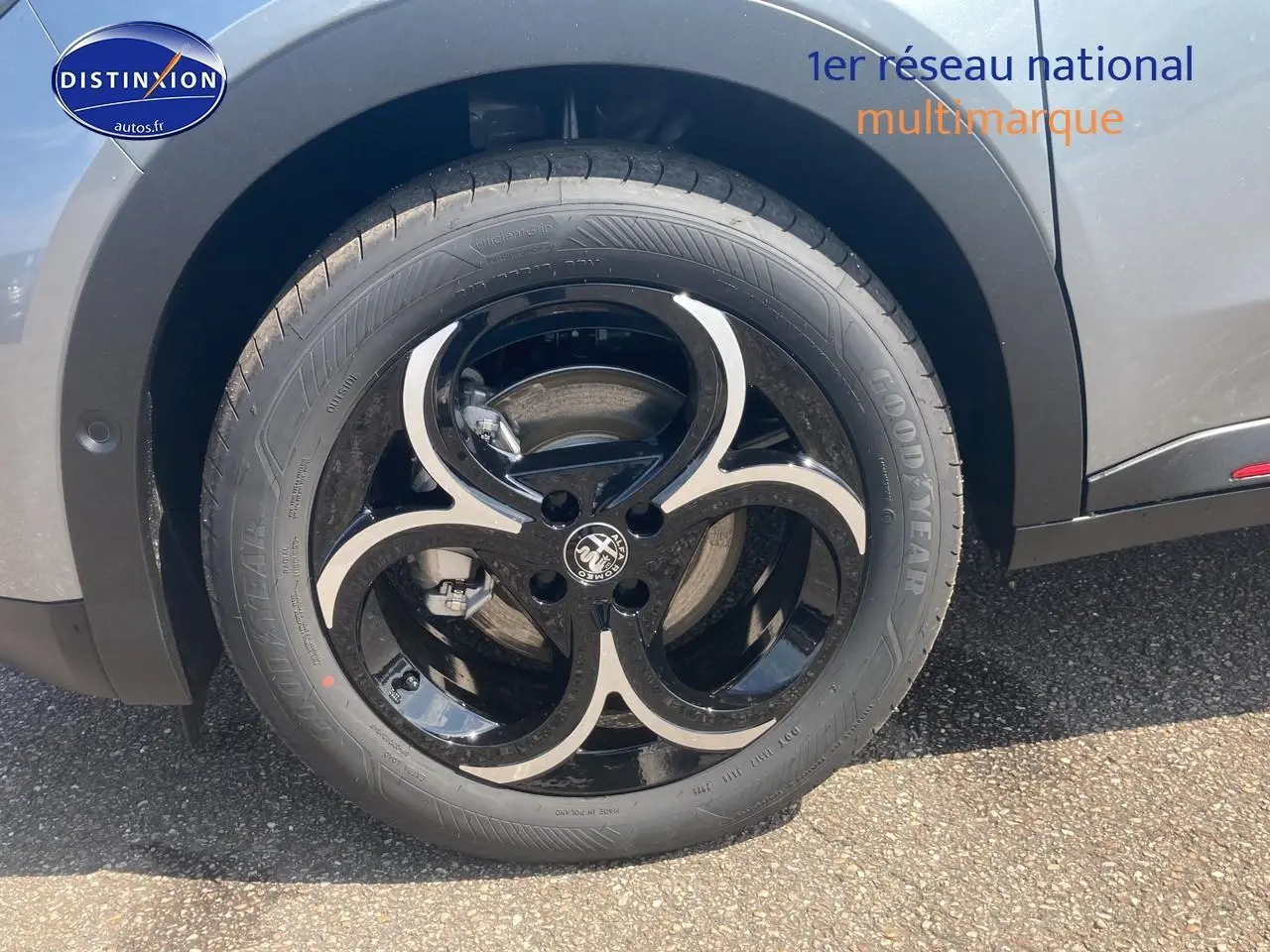 Gros plan sur la roue avant droite de l'Alfa Romeo Junior 1.2 hybride gris t/noir avec jante alliage noire et argent.