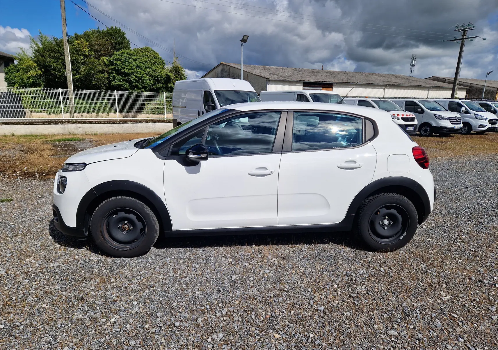 Vue latérale droite d'une Citroën C3 Société blanche de 2021 avec jantes acier noires sur un parking extérieur.