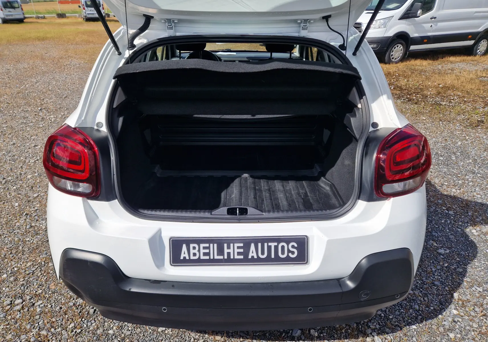 Vue arrière ouverte du coffre d'une Citroën C3 Société blanche, avec feux arrière rouges et pare-chocs noir.