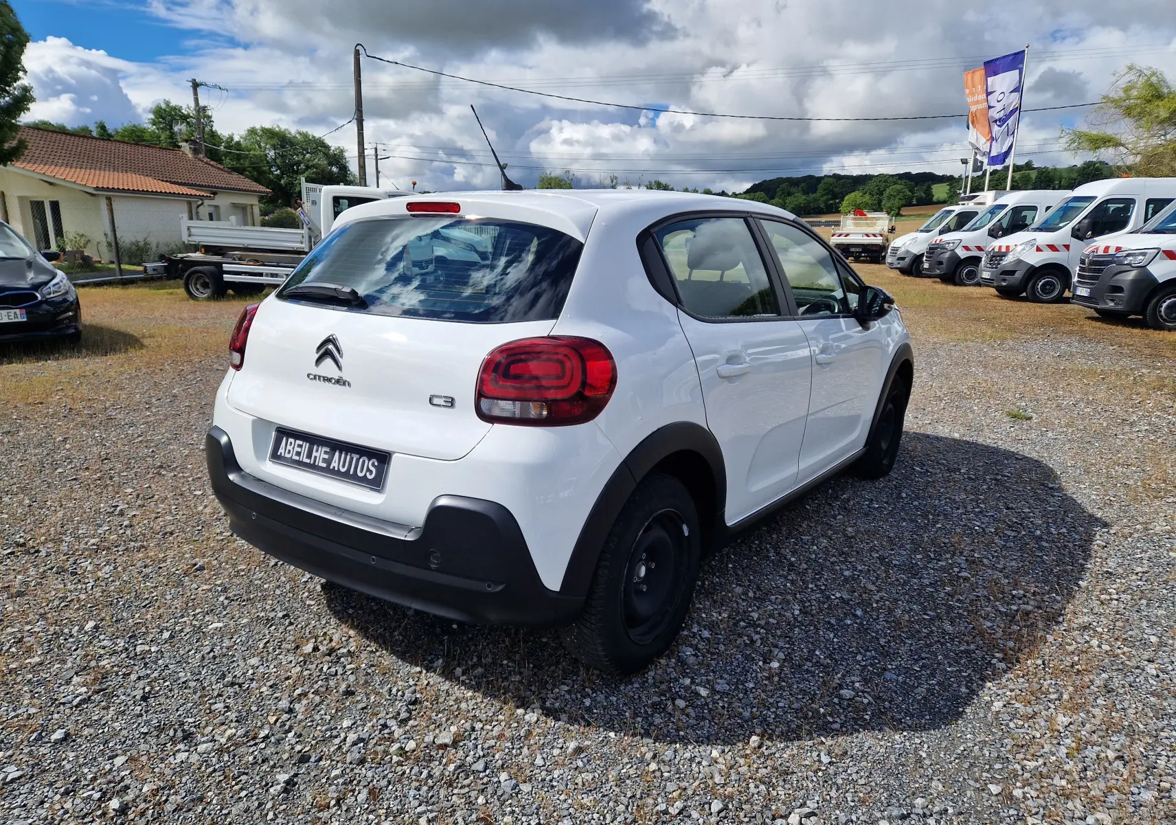 Vue 3/4 arrière droite d'une Citroën C3 Société blanche 2021 avec pare-chocs noirs et jantes tôles noires.