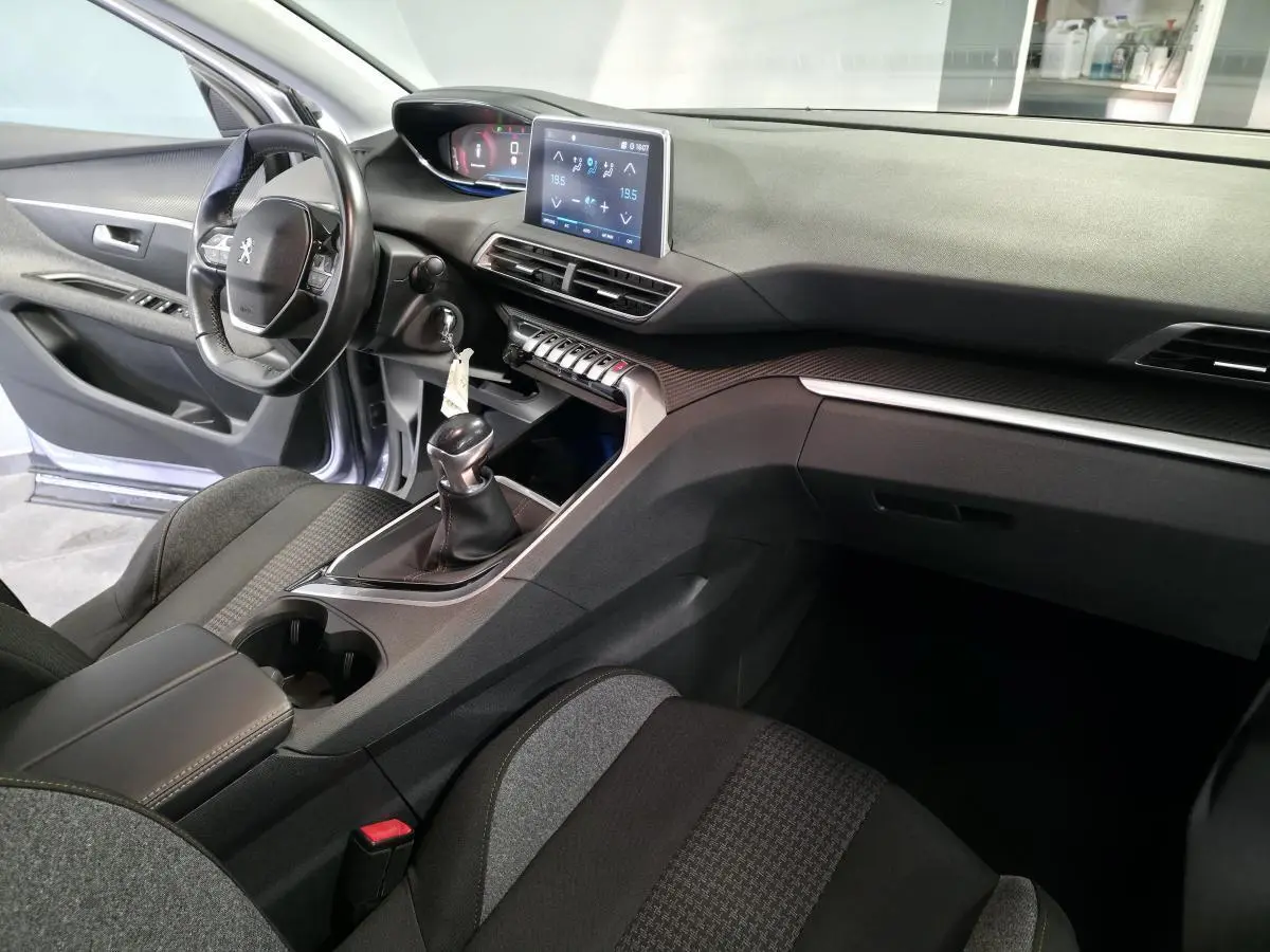 Vue intérieure côté conducteur du Peugeot 3008 gris, mettant en valeur le tableau de bord avec écran tactile et la boîte manuelle.